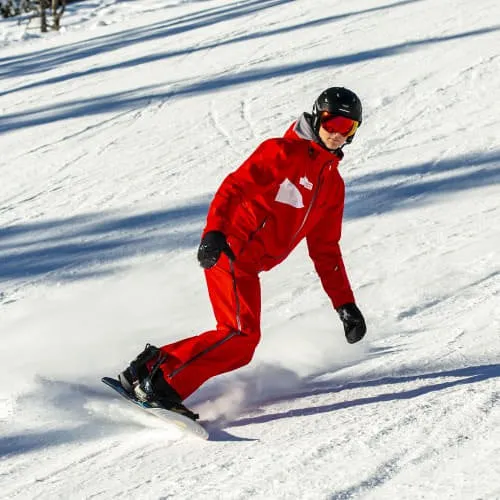 Person in roter Ausrüstung snowboardet im Schnee