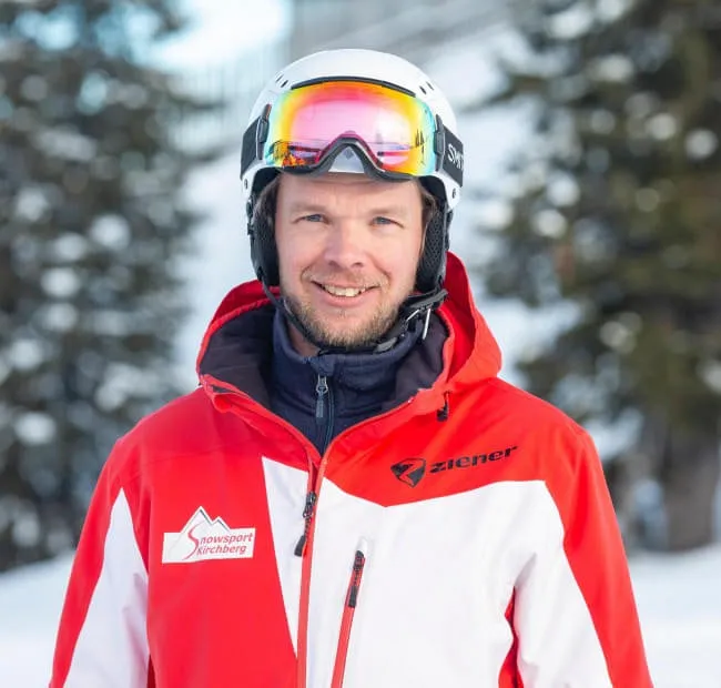 Skier in snow wearing a red jacket and helmet