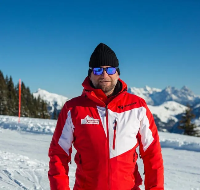 Man in red ski jacket with sunglasses in the snow