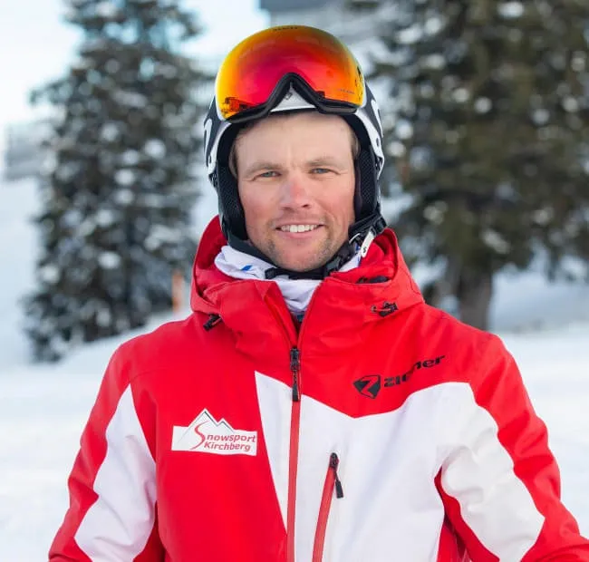 Ski instructor in a red jacket against a snowy background