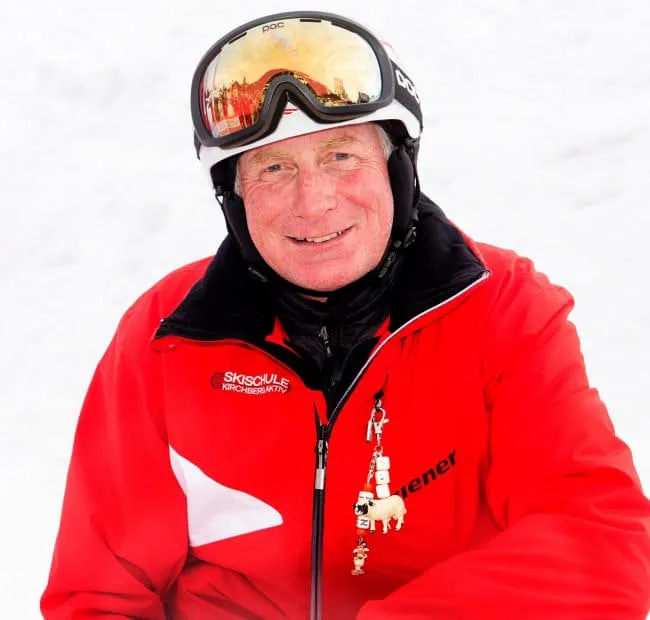 Smiling man in red ski jacket against snowy background