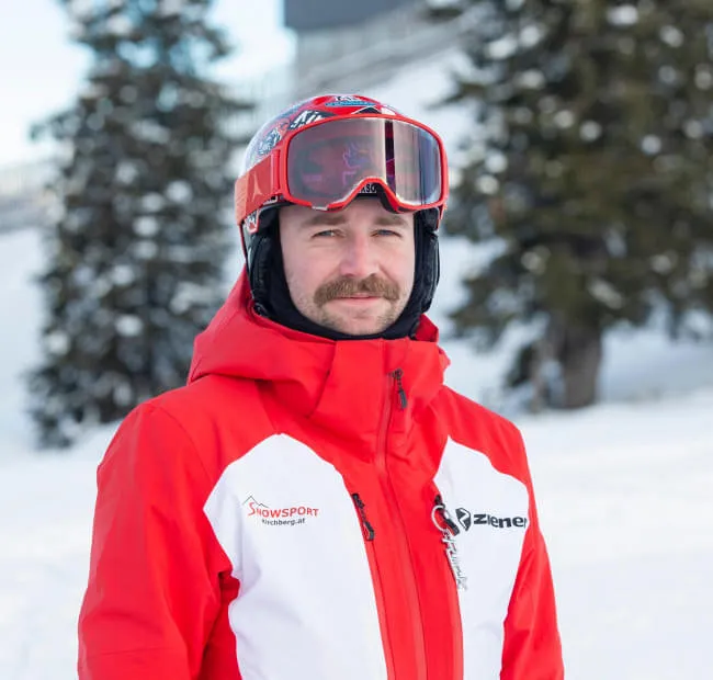 Man in red ski gear with goggles on snow