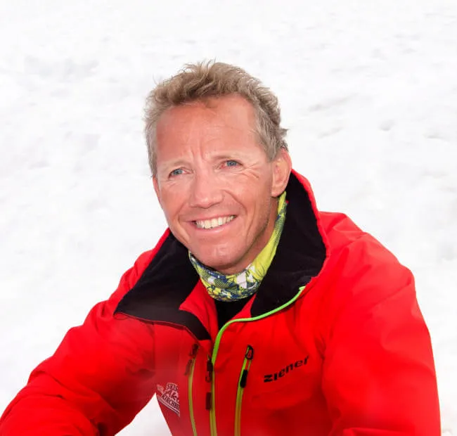Person in red jacket smiling in the snow.