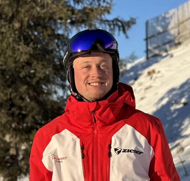 Skier in red jacket with trees in background