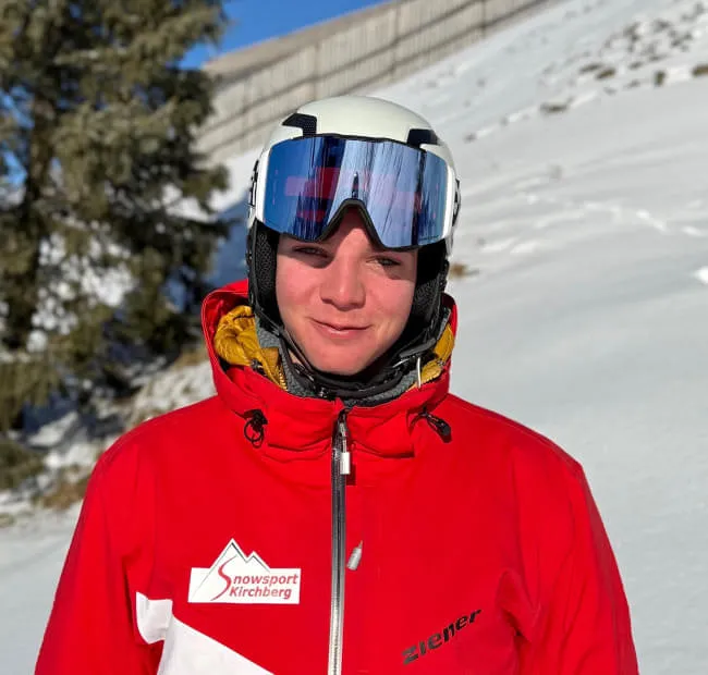 Young skier in red jacket on snow