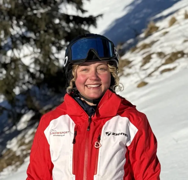 Smiling skier in red jacket on snow hill