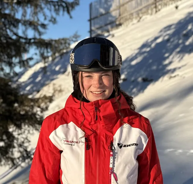 Smiling skier in red jacket in snowy landscape