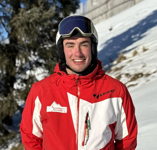 Young skier in red outfit against snowy background
