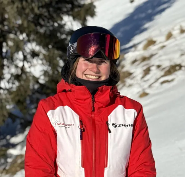 Smiling skier in red jacket on the snow