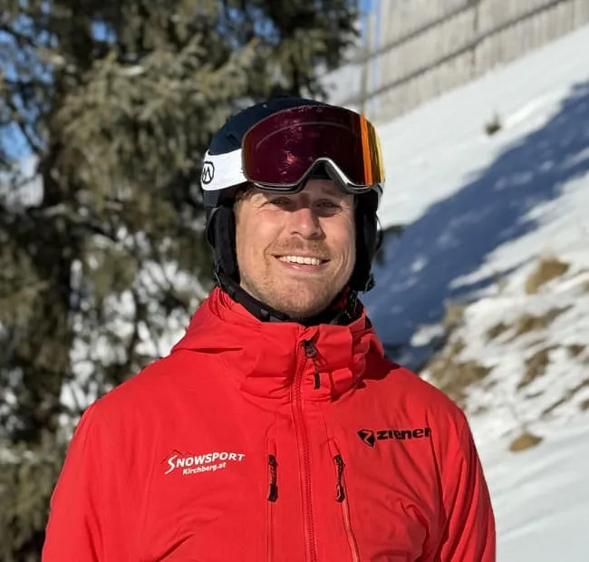 Smiling skier in red jacket on snowy slope