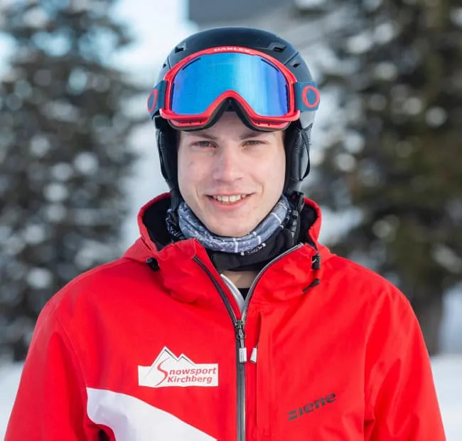 Man in ski gear wearing red jacket, snow in background