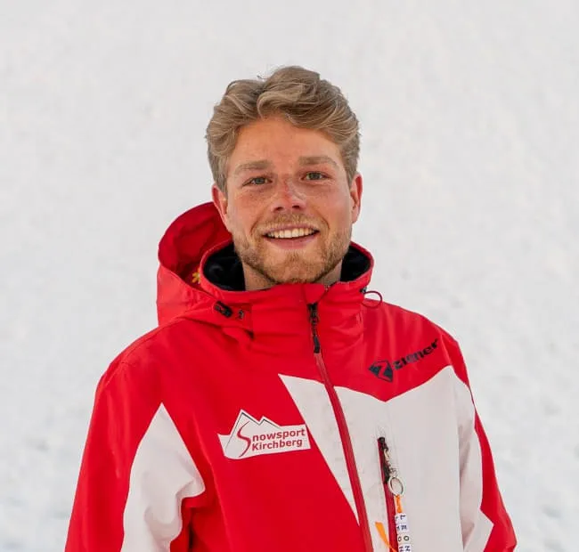 Man with blonde hair in a red jacket, snowy background