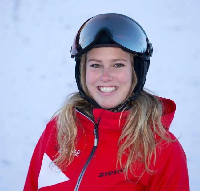 Smiling skier in red attire with ski goggles outdoors