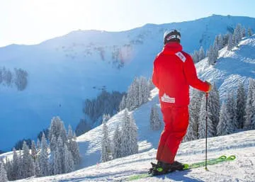 Skiër in rode outfit op besneeuwde berghelling