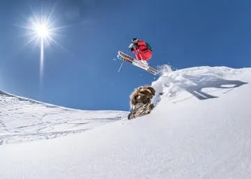 Skiër springt over een hond in de sneeuw.