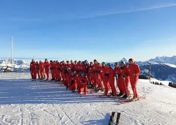 Groep skiërs in rode pakken op de sneeuw
