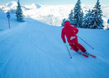 Skiër in rode kleding op een besneeuwde piste