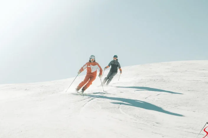 Zwei Skifahrer auf einer verschneiten Piste